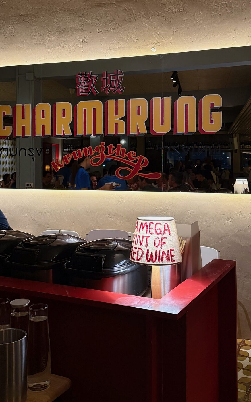 The Charmkrung sign, in red and gold lettering above the restaurant's open bar.